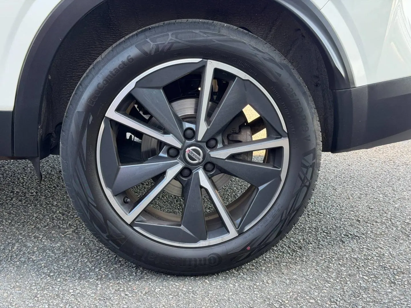 Gros plan sur la roue avant droite avec jante alliage noire et argent du Nissan Qashqai blanc.