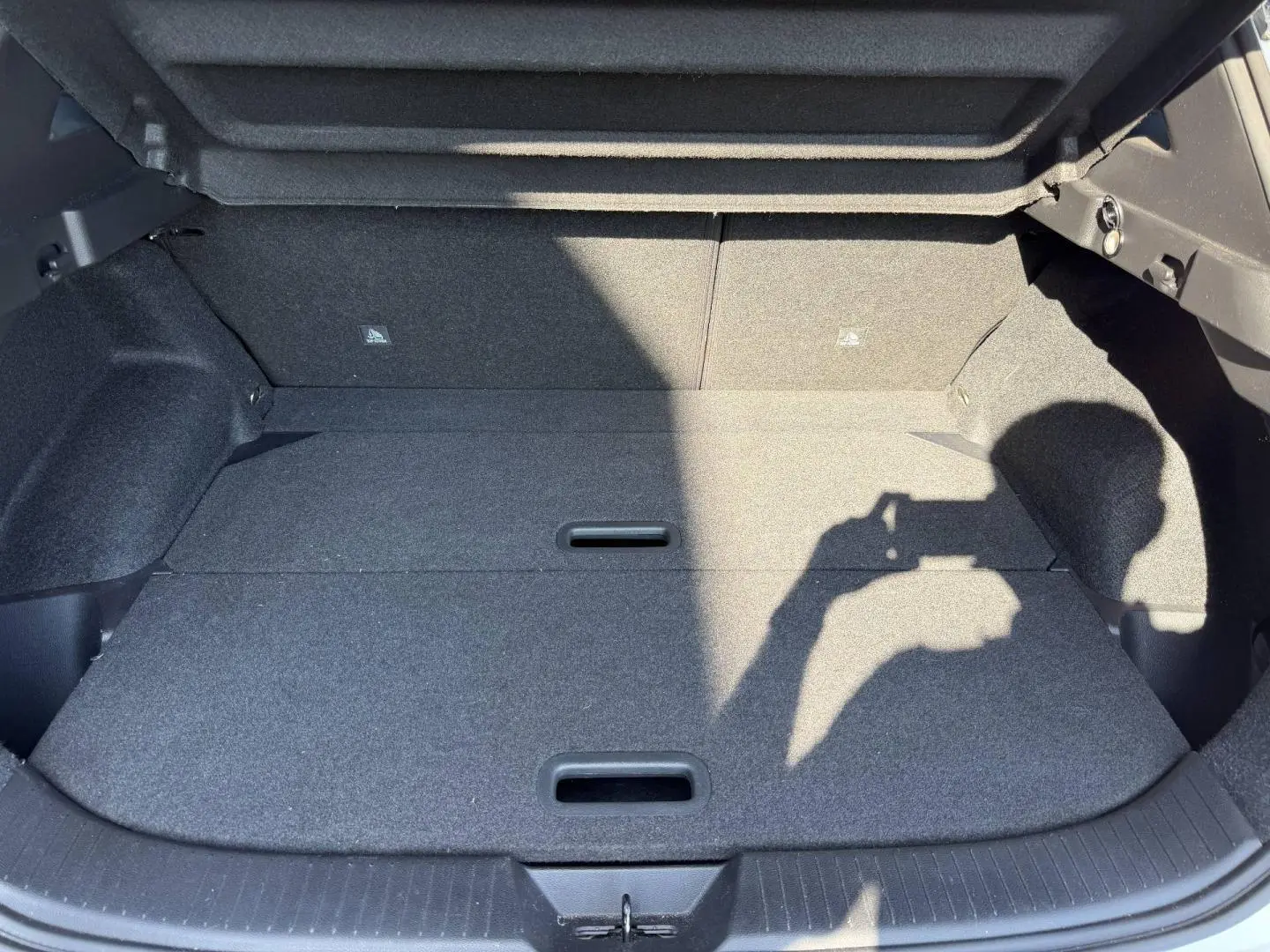 Coffre spacieux gris foncé du Nissan Qashqai 1.3 Mild Hybrid 2022, vue intérieure avec plancher plat et poignées intégrées.