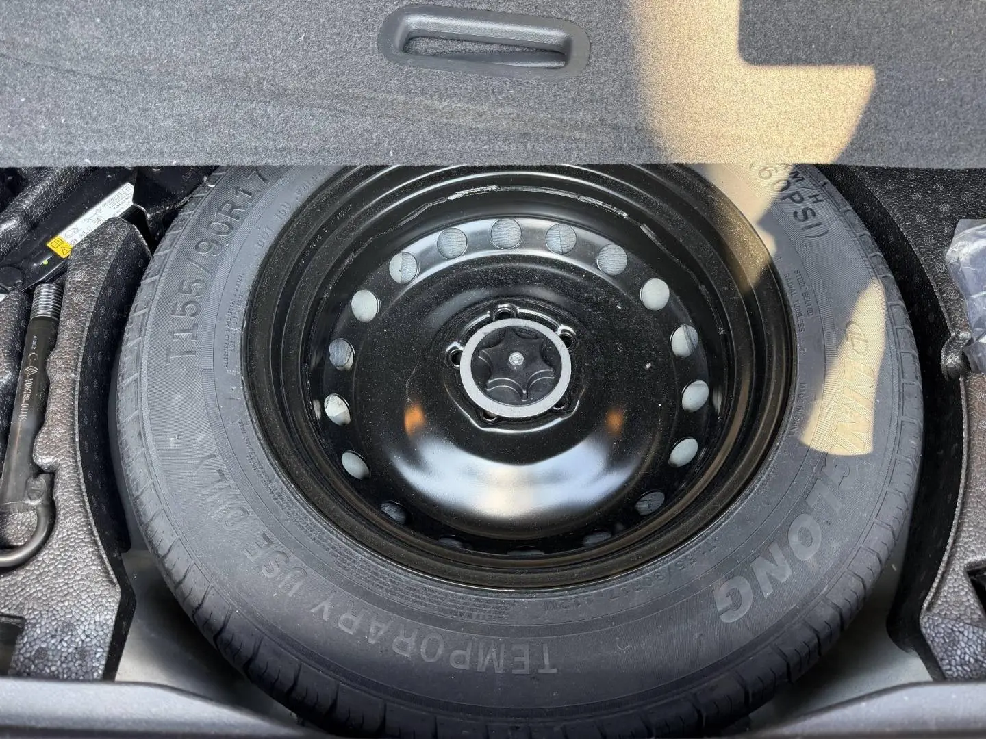 Roue de secours noire vue de dessus dans le coffre du Nissan Qashqai 1.3 Mild Hybrid rouge 2022.