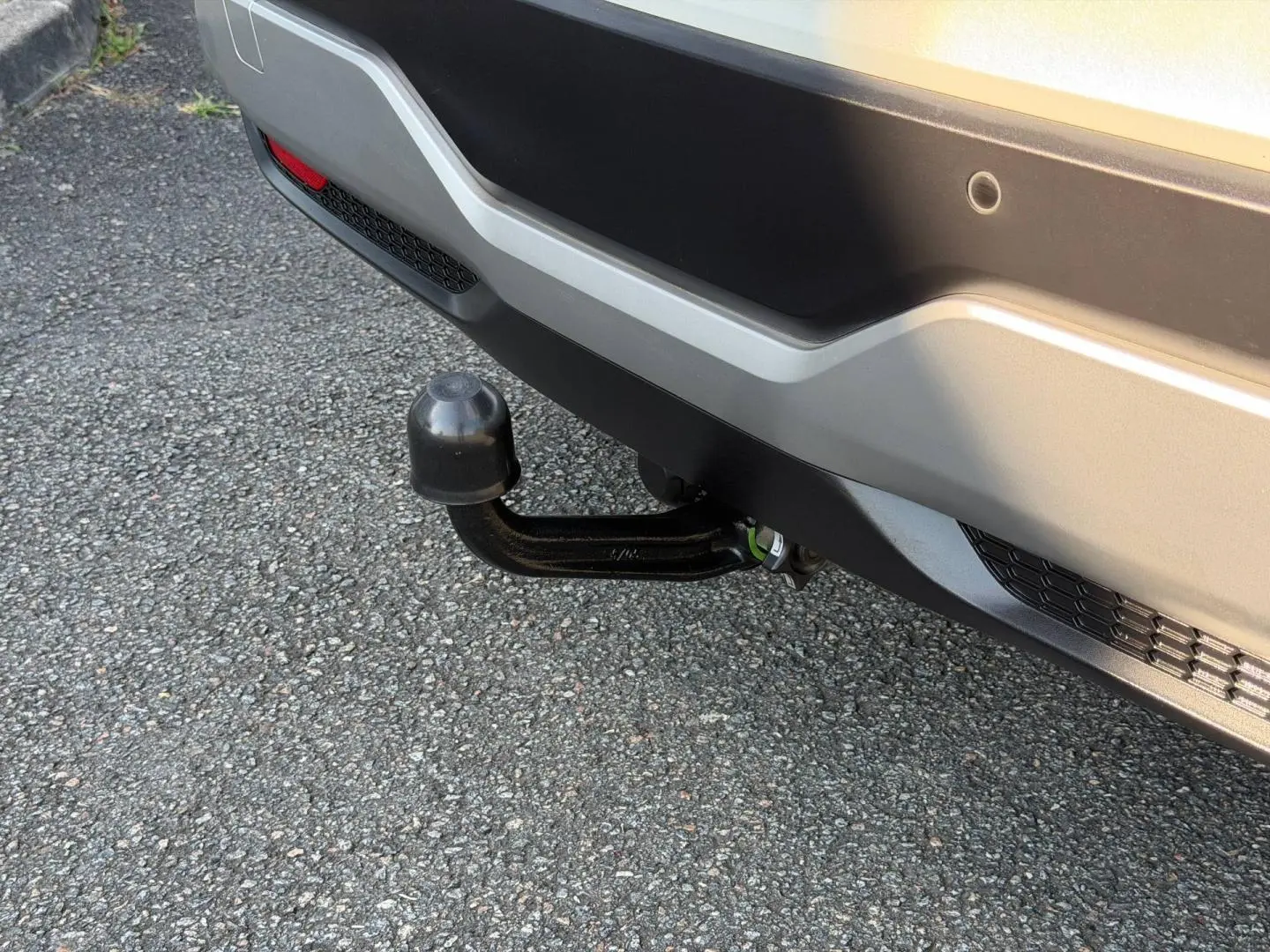 Gros plan sur l'attelage noir sous le pare-chocs arrière gris clair du Nissan Qashqai 2022.