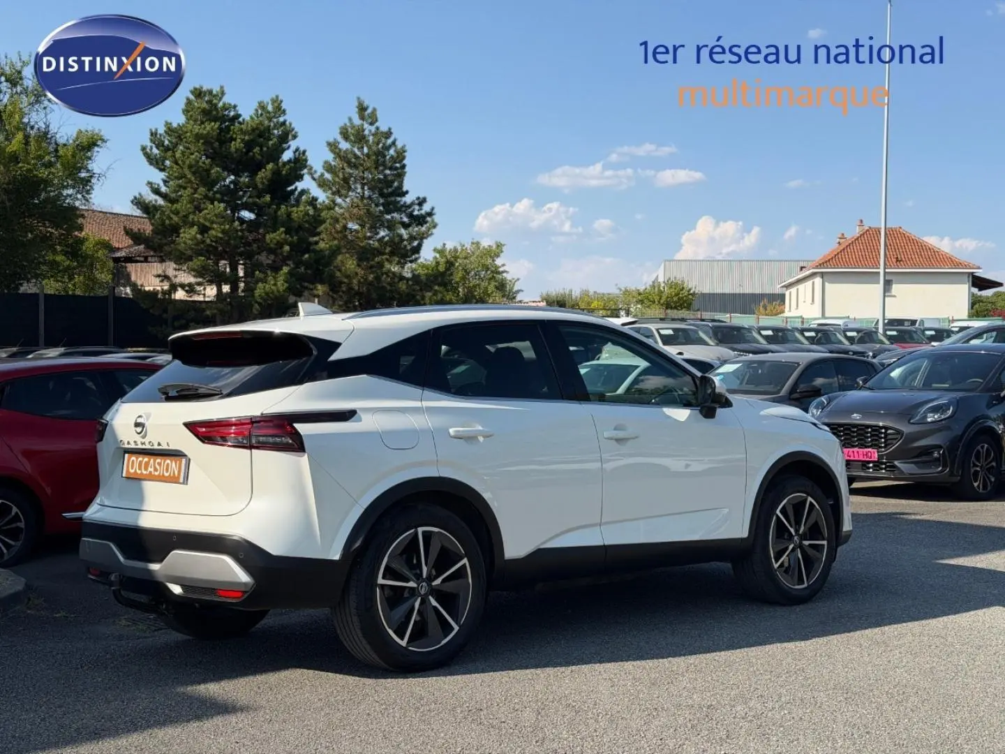 Nissan Qashqai blanc en 3/4 arrière droit sur parking, avec jantes alliage et feux arrière LED distinctifs.