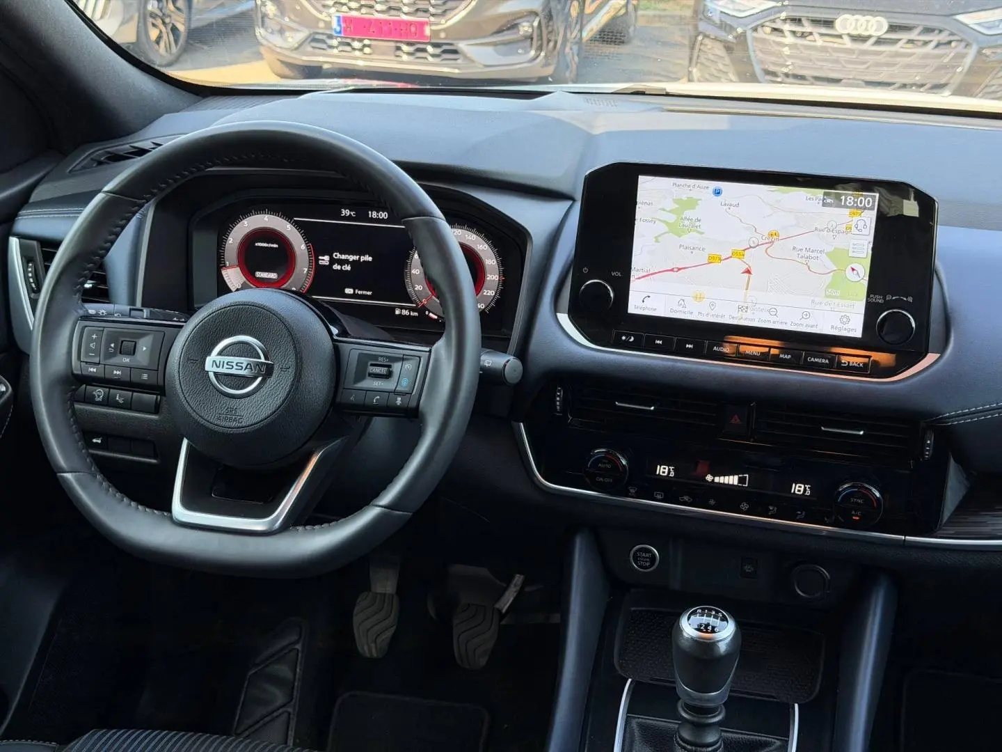 Vue intérieure frontale du tableau de bord du Nissan Qashqai 2022 avec volant cuir, écran tactile GPS et boîte manuelle.