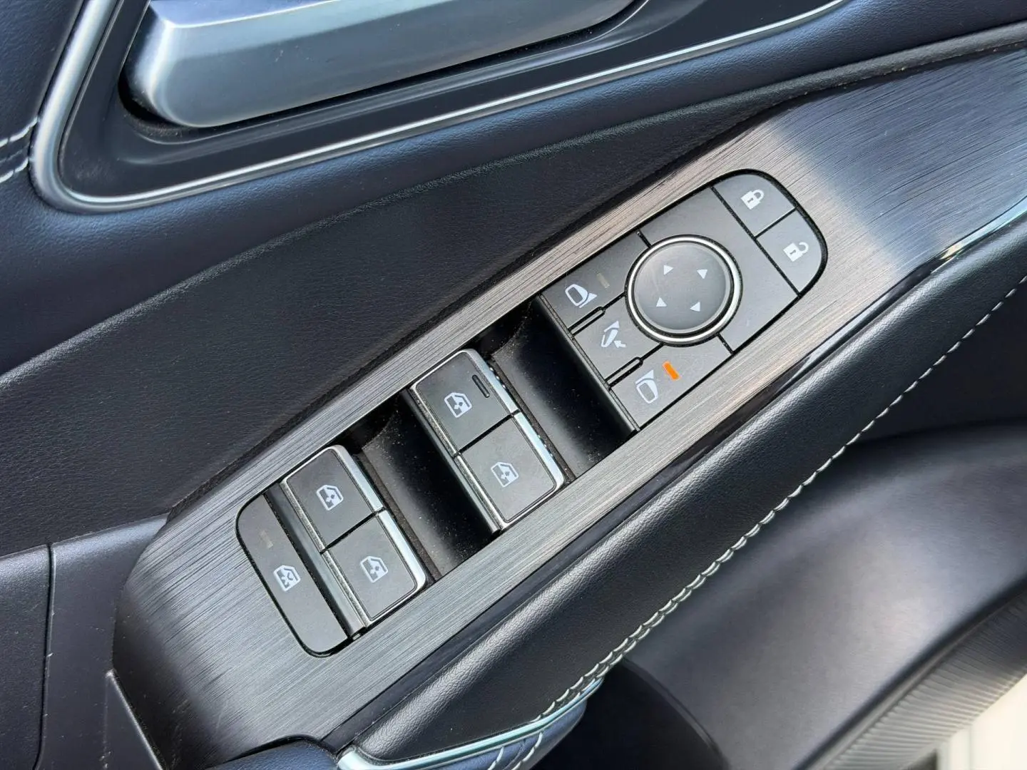 Gros plan sur la commande des vitres et rétroviseurs côté conducteur intérieur noir du Nissan Qashqai Tekna 2022.