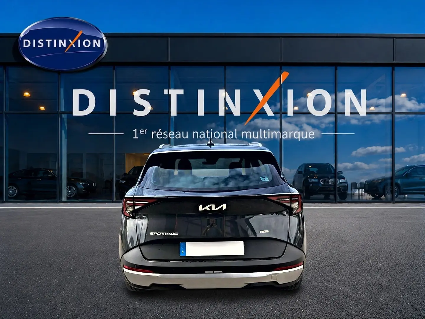 Vue arrière d'un KIA Sportage 1.6 hybride gris eclipse, avec feux arrière LED et barres de toit visibles.