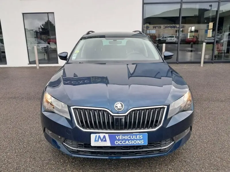 Vue frontale d'une Skoda Superb Combi 2018 bleu métal avec calandre chromée et feux allumés.