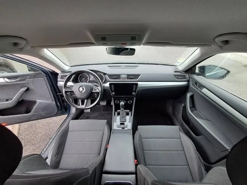 Intérieur de la Skoda Superb Combi 2018 bleu métal, vue frontale du tableau de bord et des sièges avant ouverts.