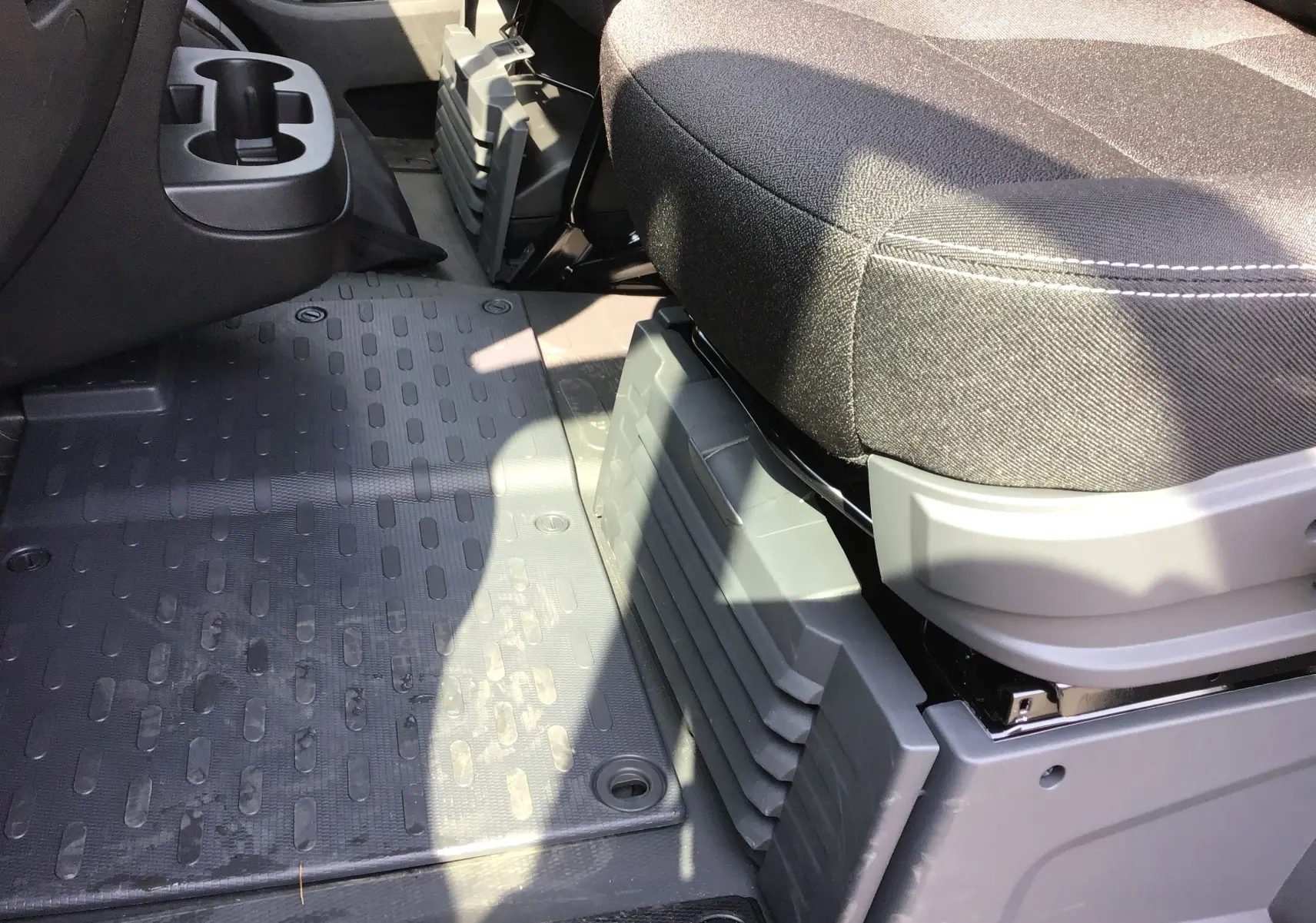 Détail de l'espace au sol côté passager avec siège tissu gris et tapis caoutchouc noir du Peugeot Boxer Fourgon 2025.