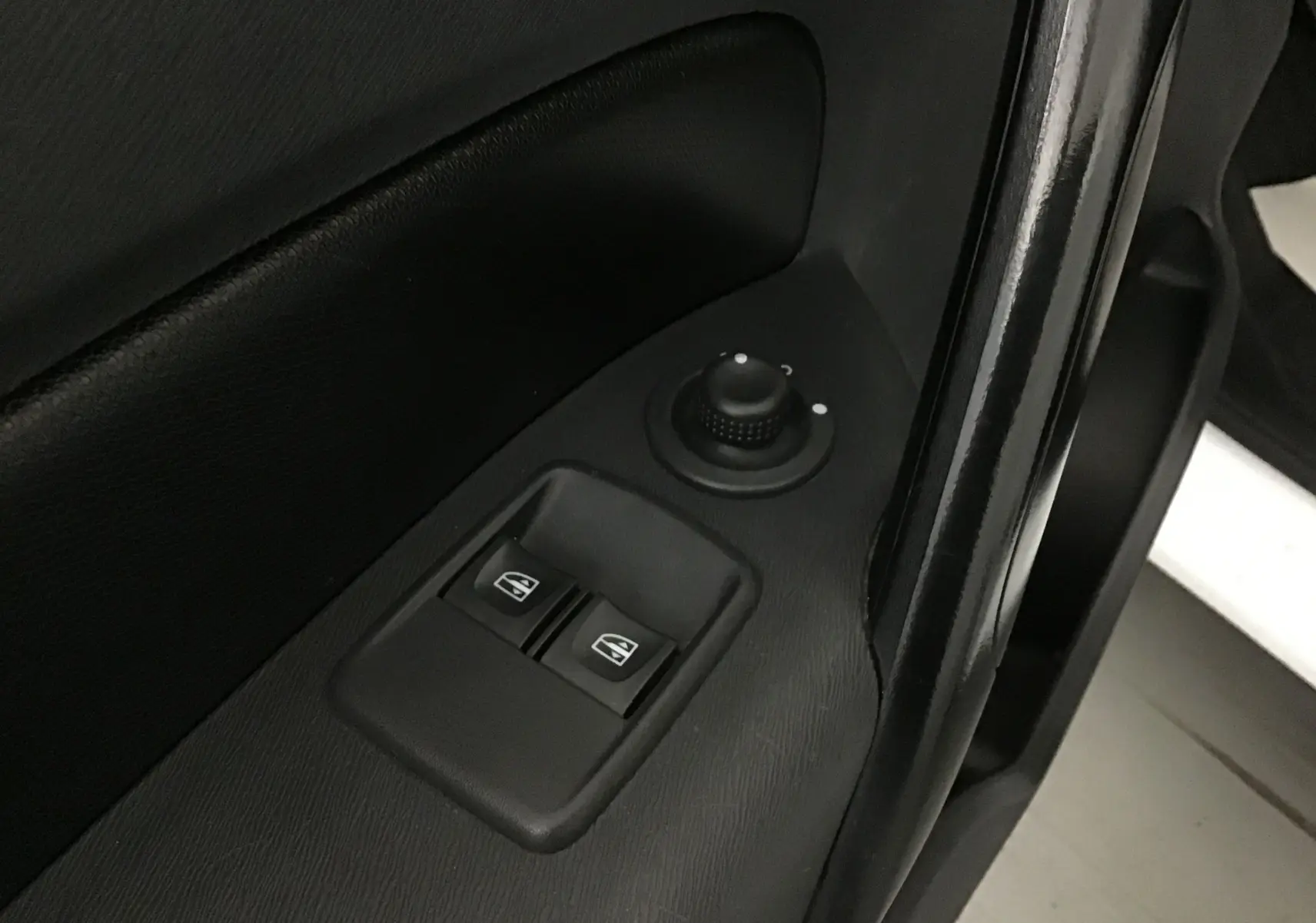 Gros plan sur les commandes électriques des vitres et le réglage des rétroviseurs sur la porte côté gauche d’un Renault Kangoo blanc 2021.