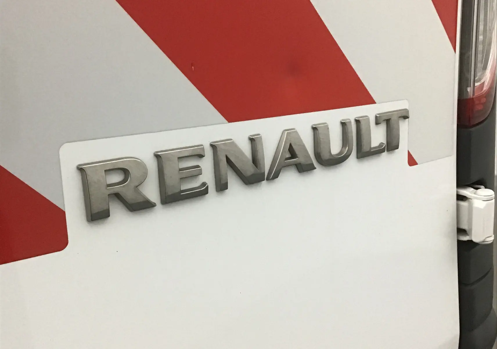Gros plan sur l'arrière droit blanc du Renault Kangoo 2021 avec marquage rouge et logo Renault en relief.