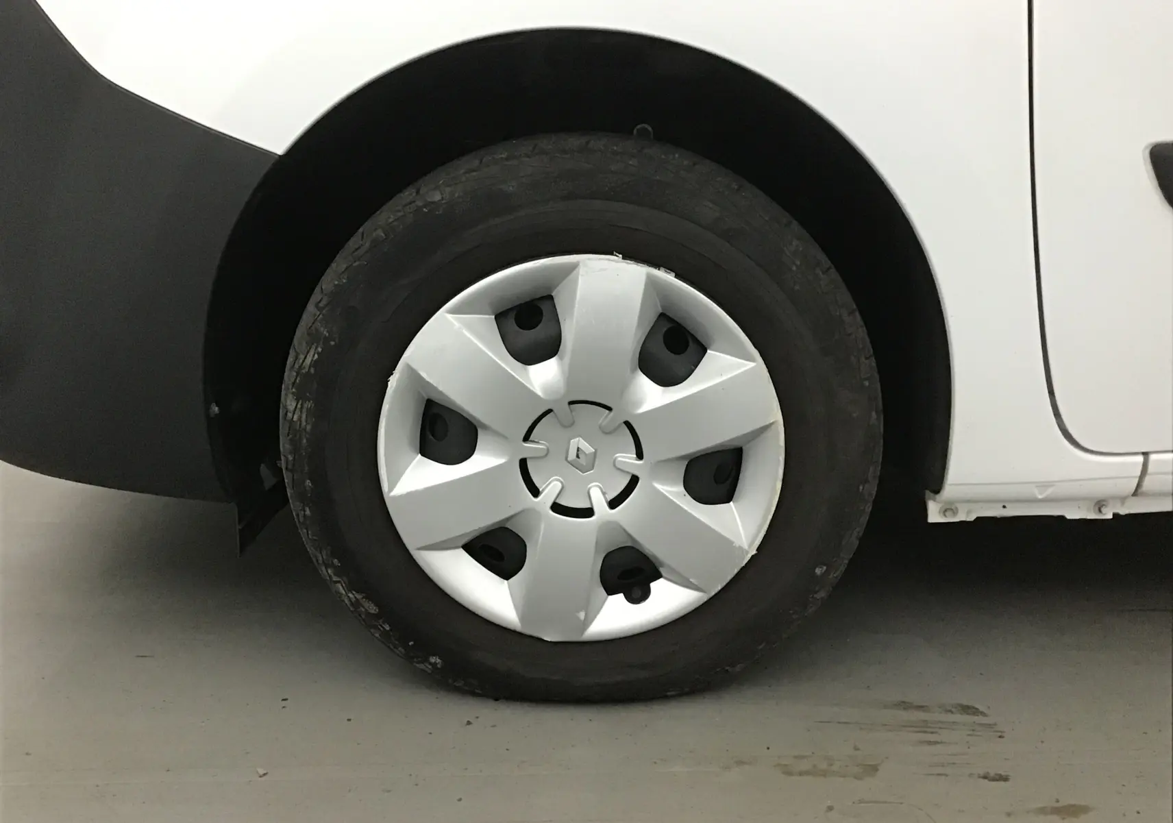 Gros plan sur la roue avant gauche blanche d'un Renault Kangoo 1.5 Blue dCi 95 Extra R-Link 2021 avec enjoliveur d'origine.