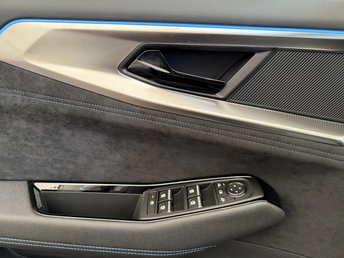 Détail de la porte côté conducteur de Renault Espace 2025 esprit Alpine, avec garniture noire et surpiqûres bleues.