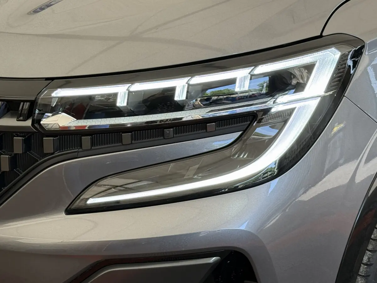 Gros plan sur le phare avant droit allumé du Renault Espace gris foncé esprit Alpine 2025 avec signature lumineuse LED distinctive.