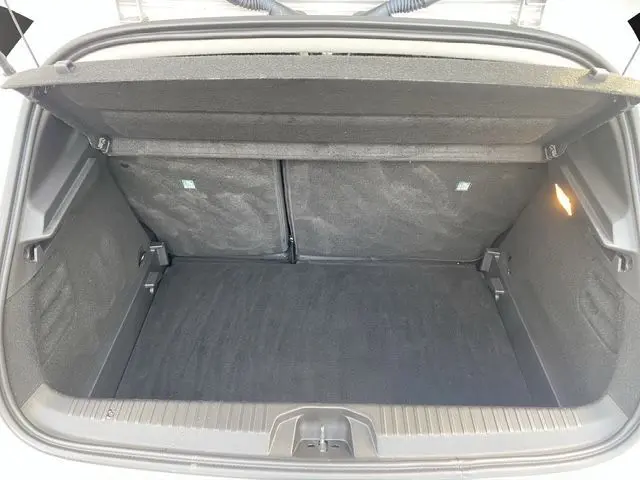 Vue intérieure du coffre spacieux et compartimenté de la Renault Clio V gris Highland, éclairé et propre.