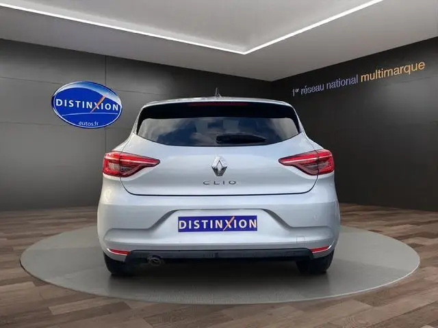 Vue arrière d'une Renault Clio V gris Highland avec vitres arrière surteintées et feux LED, en intérieur showroom.