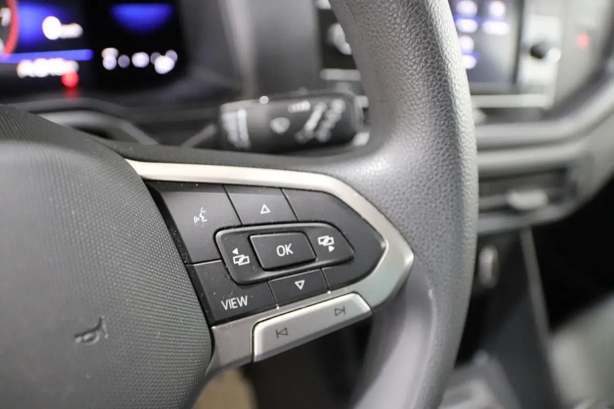 Gros plan sur les commandes multifonctions à gauche du volant noir de la Volkswagen Polo blanche, version 2022.