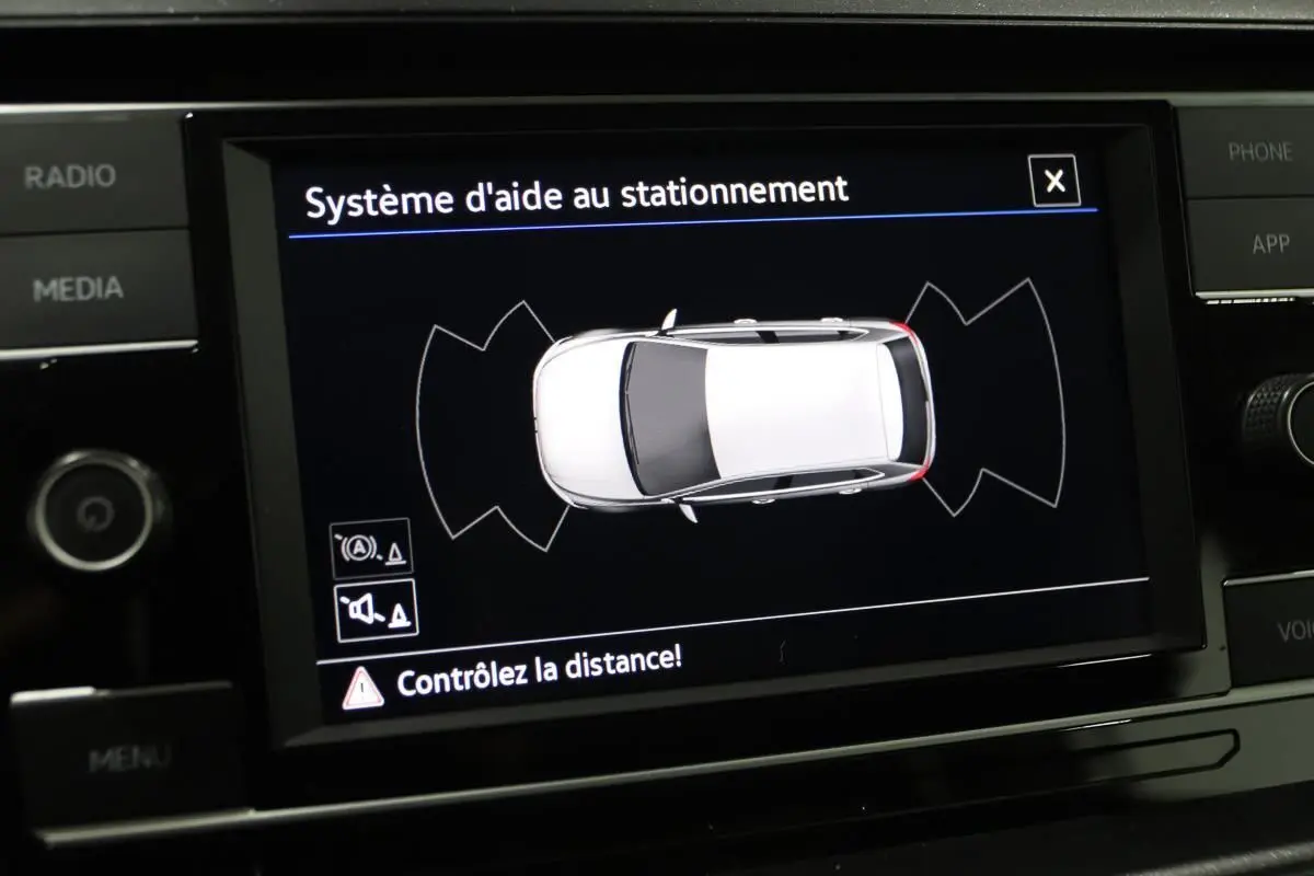 Écran central affichant le système d'aide au stationnement avec vue aérienne d'une Volkswagen Polo blanche.