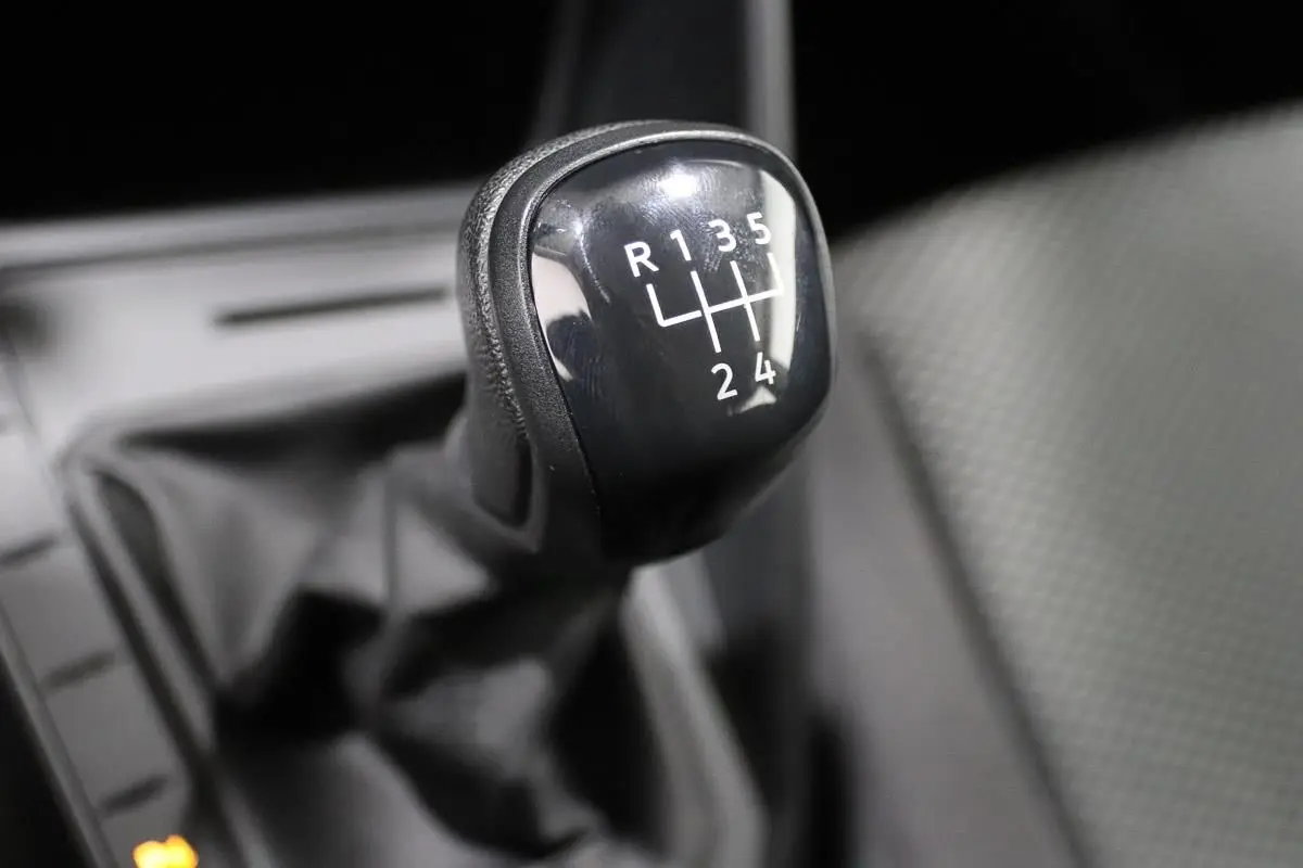 Gros plan sur le levier de vitesses manuel noir de la Volkswagen Polo 1.0 80 BVM, intérieur tissu gris.