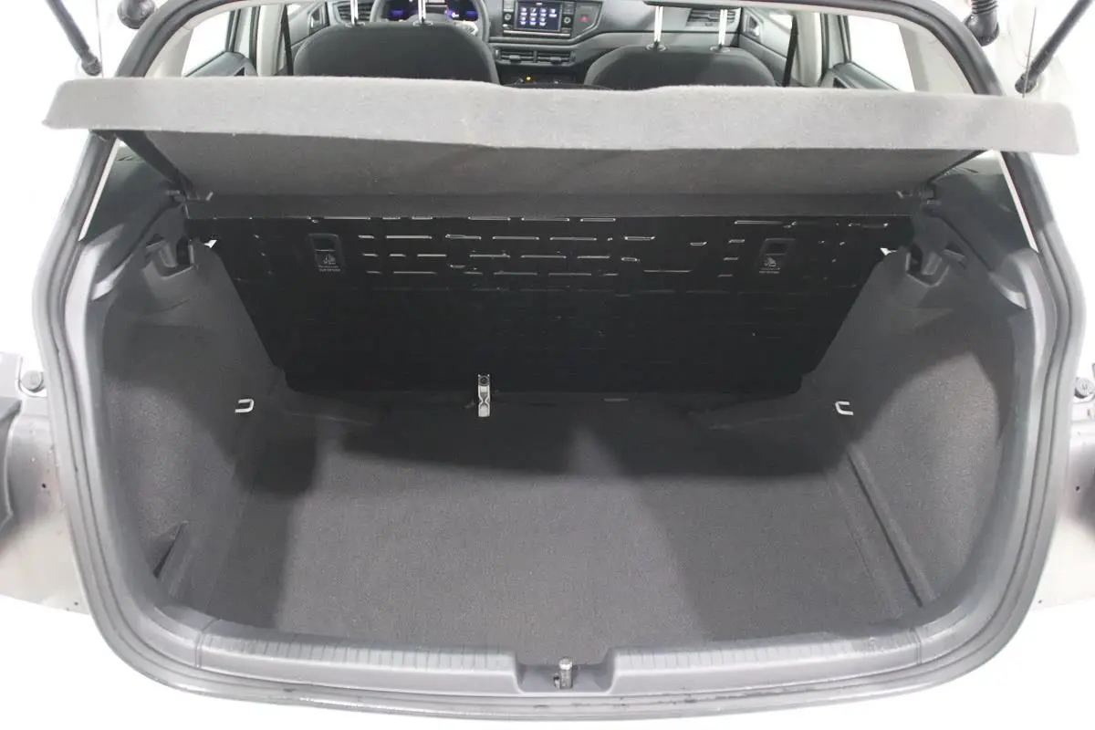 Coffre ouvert vue arrière d’une Volkswagen Polo blanche 2022, intérieur du coffre spacieux et tapis noir.