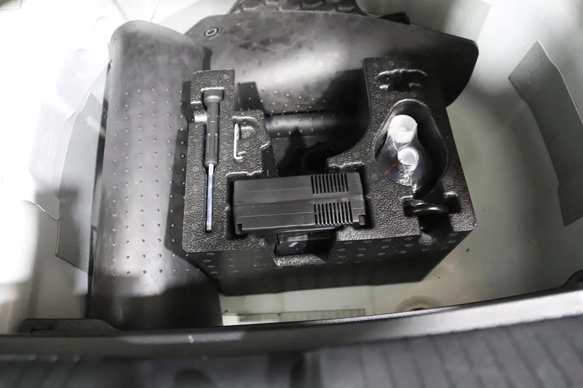 Coffre ouvert d'une Volkswagen Polo blanche 2022, montrant le rangement d'outils et accessoires sous le plancher.