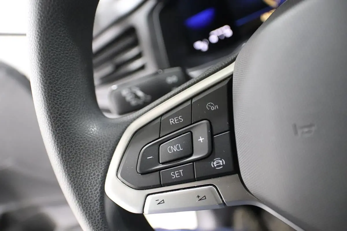 Gros plan sur les commandes de régulateur de vitesse au volant noir d'une Volkswagen Polo blanche de 2022.