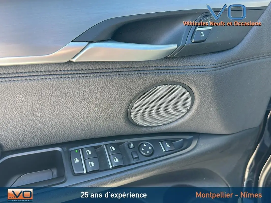 Détail de la porte côté conducteur en cuir noir avec commandes électriques et haut-parleur sur BMW X6 F16 noir.