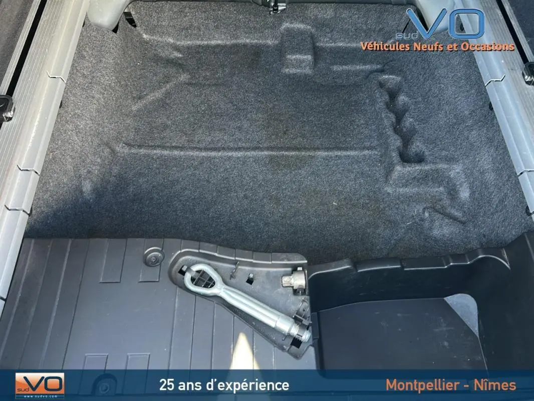 Vue plongeante sur le coffre vide d'un BMW X6 noir F16 xDrive40d 2017, avec tapis et outil de remorquage visible.