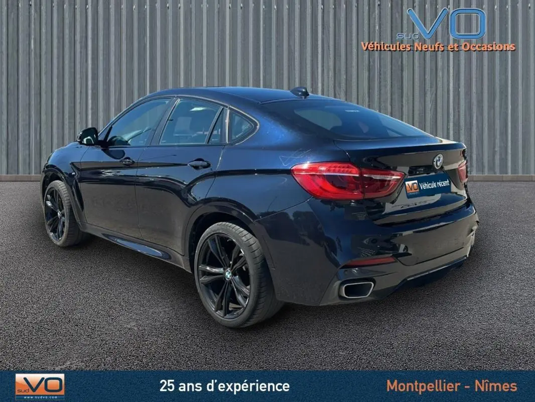 BMW X6 F16 noir en 3/4 arrière droit, mettant en valeur ses jantes alliage noires et sa silhouette sportive M Sport.