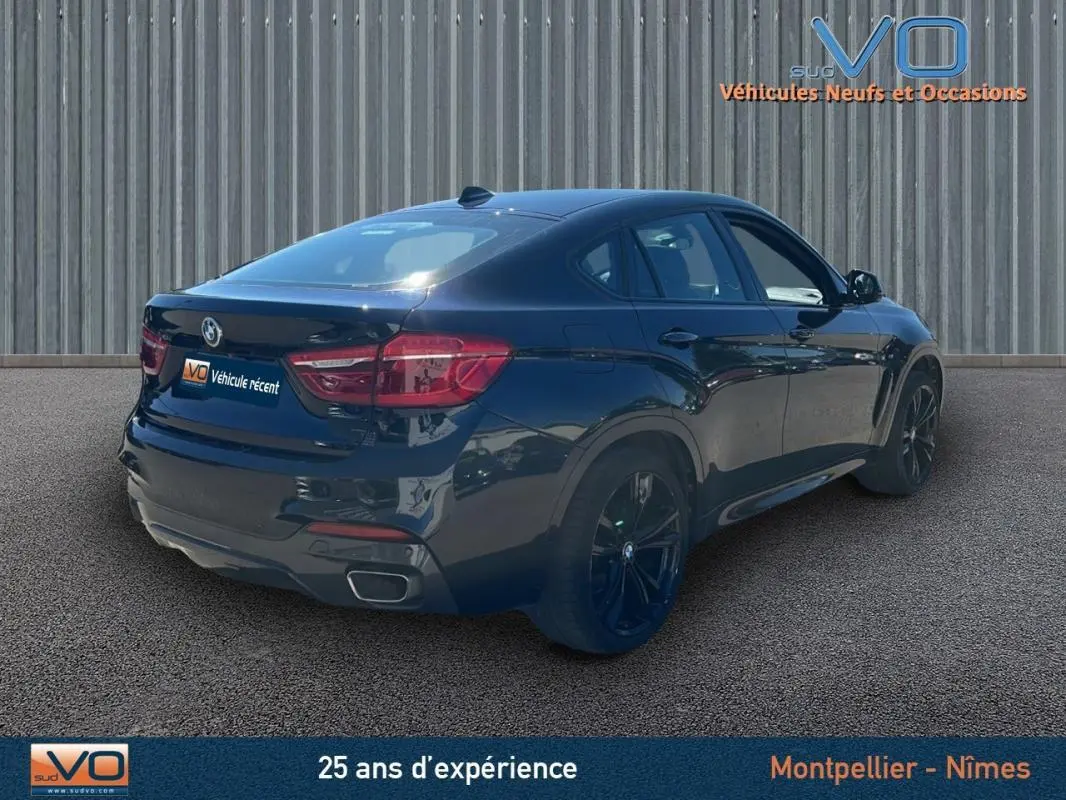 BMW X6 F16 noir en 3/4 arrière droit, mettant en valeur ses jantes alliage noires et sa silhouette coupé SUV élégante.