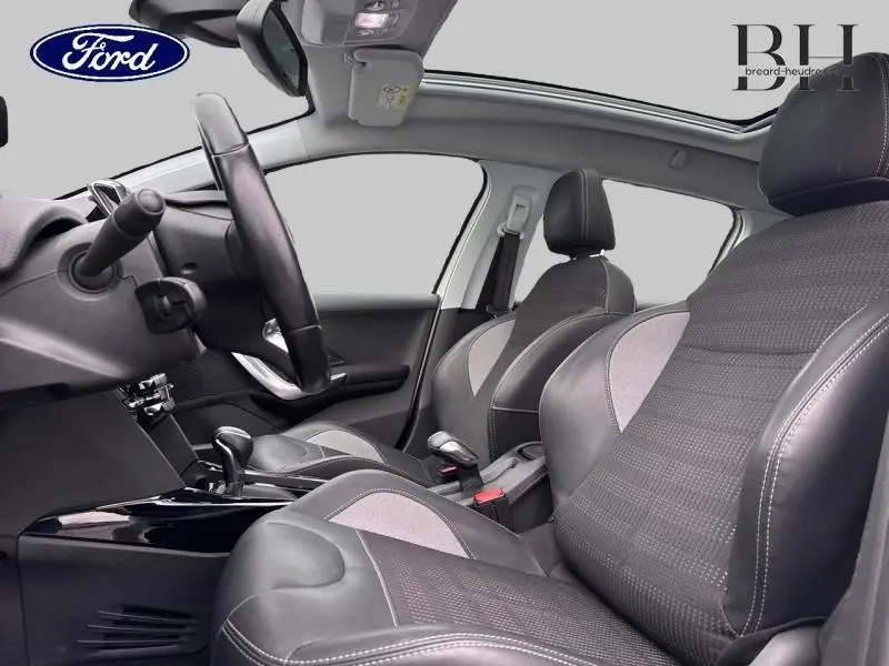 Vue intérieure côté conducteur de la Peugeot 2008 2019, sièges en cuir noir avec inserts gris et volant multifonction.