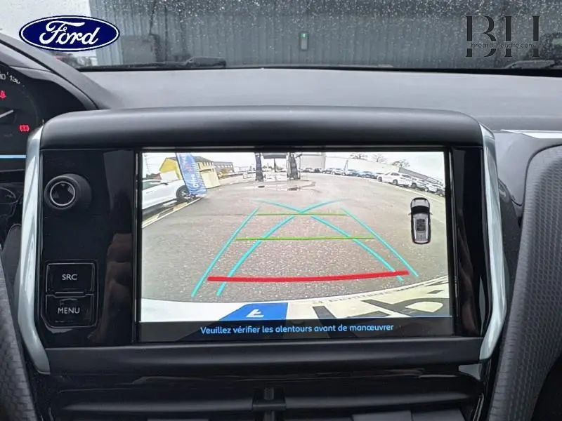 Écran de caméra de recul affichant l'arrière d'un Peugeot 2008 blanc Banquise en stationnement.