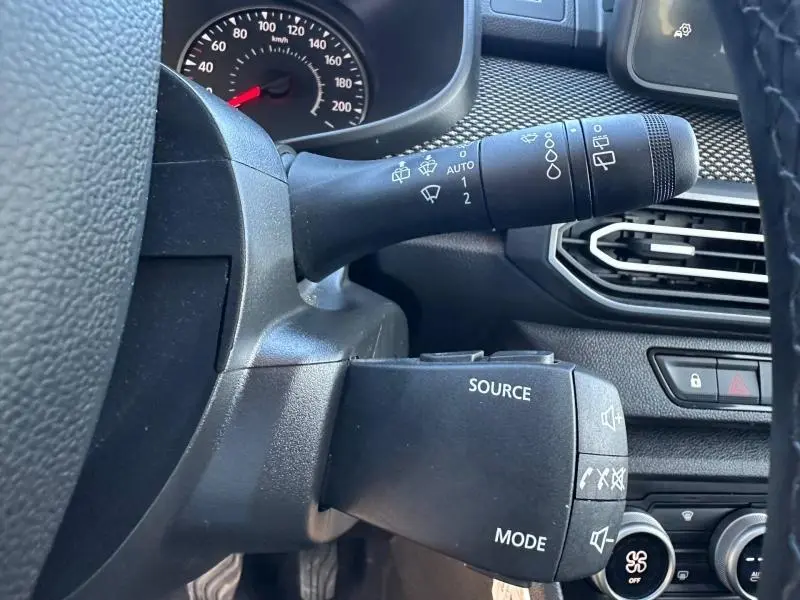 Détail intérieur du volant du Dacia Jogger 2025, montrant les commandes de phares et essuie-glaces en plastique noir.