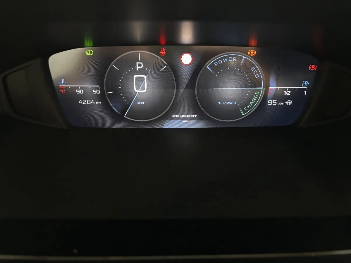 Vue rapprochée du combiné d'instruments numérique du Peugeot 308 Hybrid 145 e-DCS6 Allure affichant vitesse, charge et alertes.