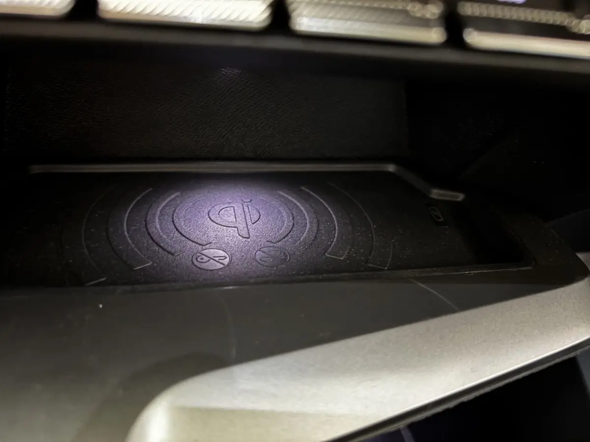 Gros plan sur le chargeur sans fil Qi intégré dans la console centrale de la Peugeot 308 Hybrid 145 e-DCS6 Allure.