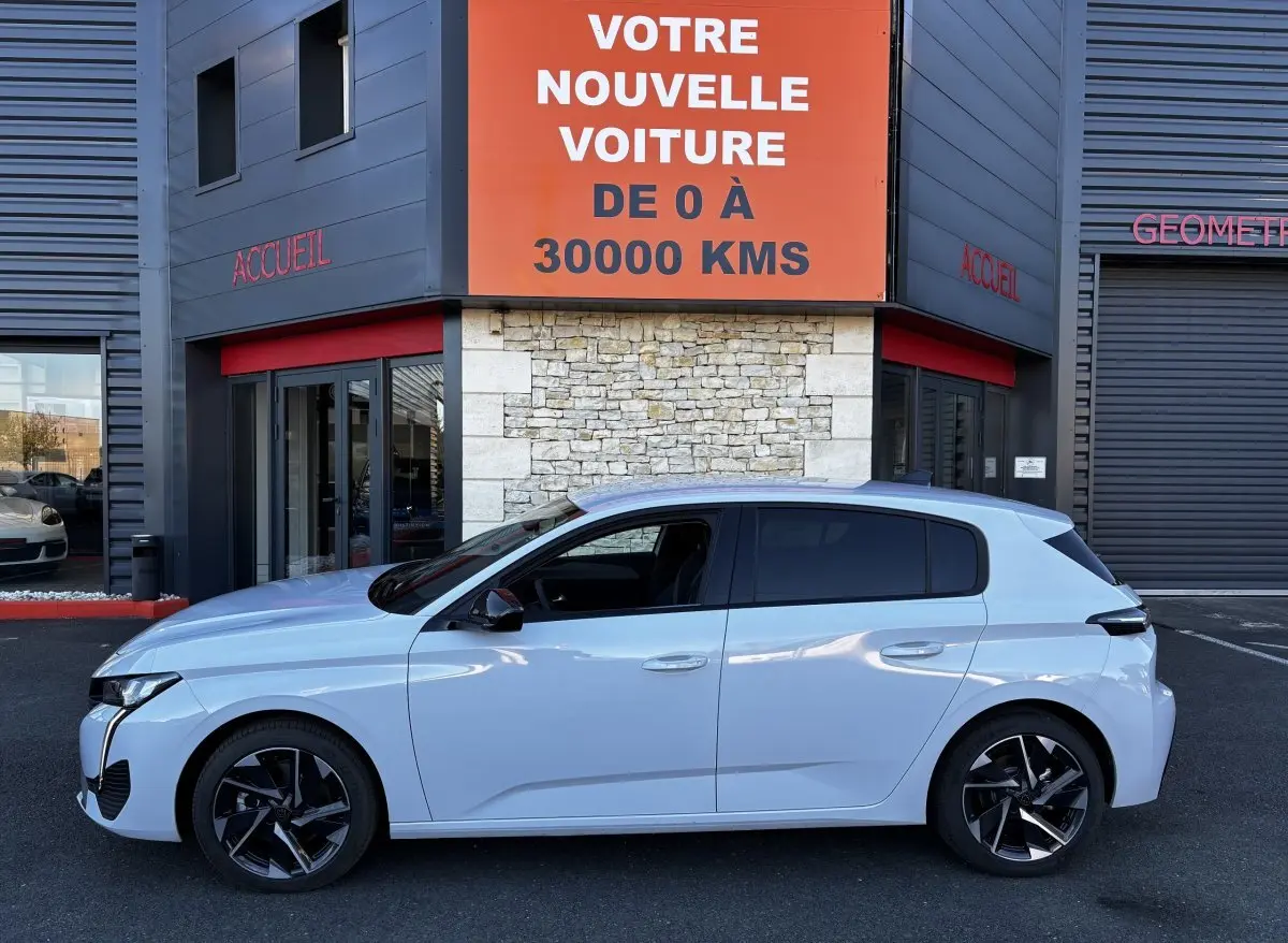 Peugeot 308 Hybrid 145 e-DCS6 Allure blanche vue de profil côté gauche, avec jantes noires et vitres teintées.