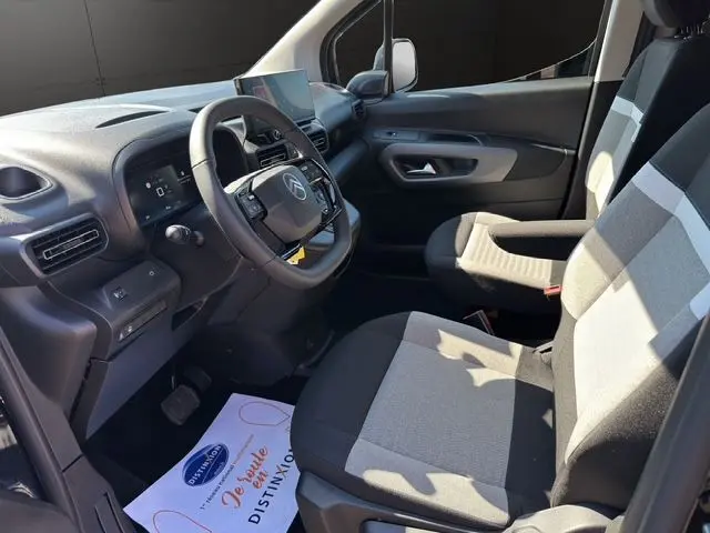 Intérieur avant droit du Citroën Berlingo noir 2025, tableau de bord moderne avec écran tactile et sièges bicolores gris et noir.