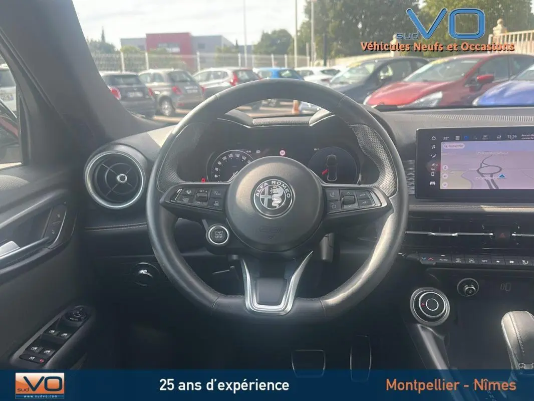 Vue centrée sur le volant sport de l'Alfa Romeo Tonale rouge 2024, avec tableau de bord et écran tactile visibles.