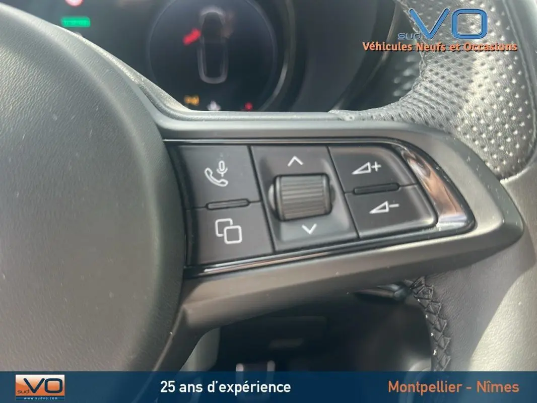 Gros plan sur les commandes du volant sport de l'Alfa Romeo Tonale rouge 2024, avec molette et boutons multifonctions.