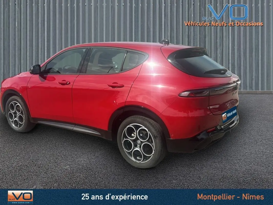 Vue 3/4 arrière gauche d'un Alfa Romeo Tonale rouge 2024 avec jantes distinctives et vitres teintées.