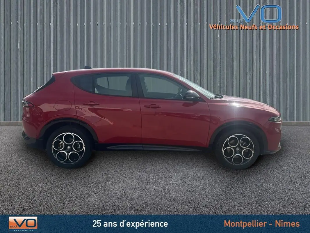 Profil latéral gauche d'une Alfa Romeo Tonale rouge 2024 avec jantes distinctives et rétroviseurs noirs.