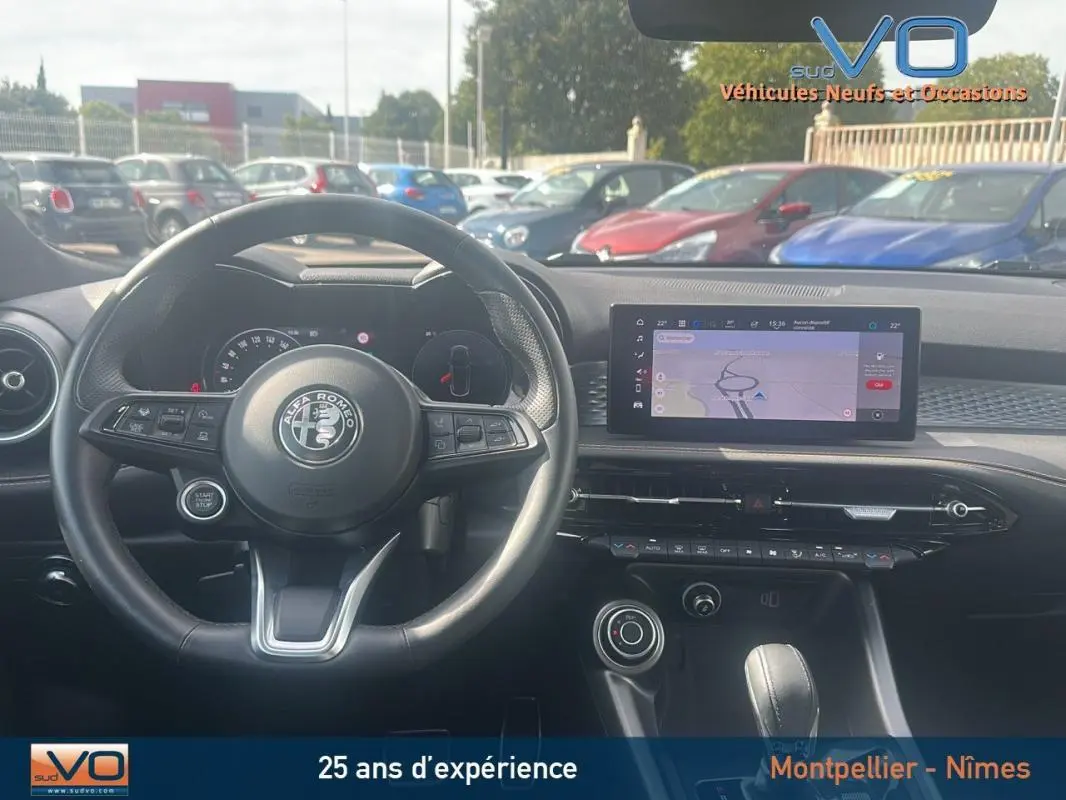 Vue intérieure centrée sur le volant sport et l'écran tactile du tableau de bord de l'Alfa Romeo Tonale rouge 2024.