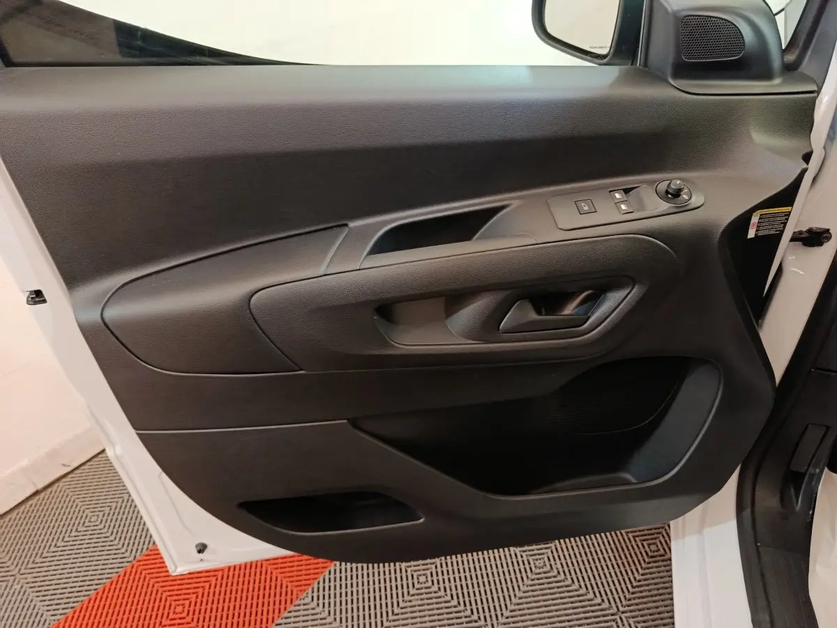 Vue intérieure de la porte avant gauche noire du Peugeot Partner blanc, avec commandes électriques et poignée intégrée.
