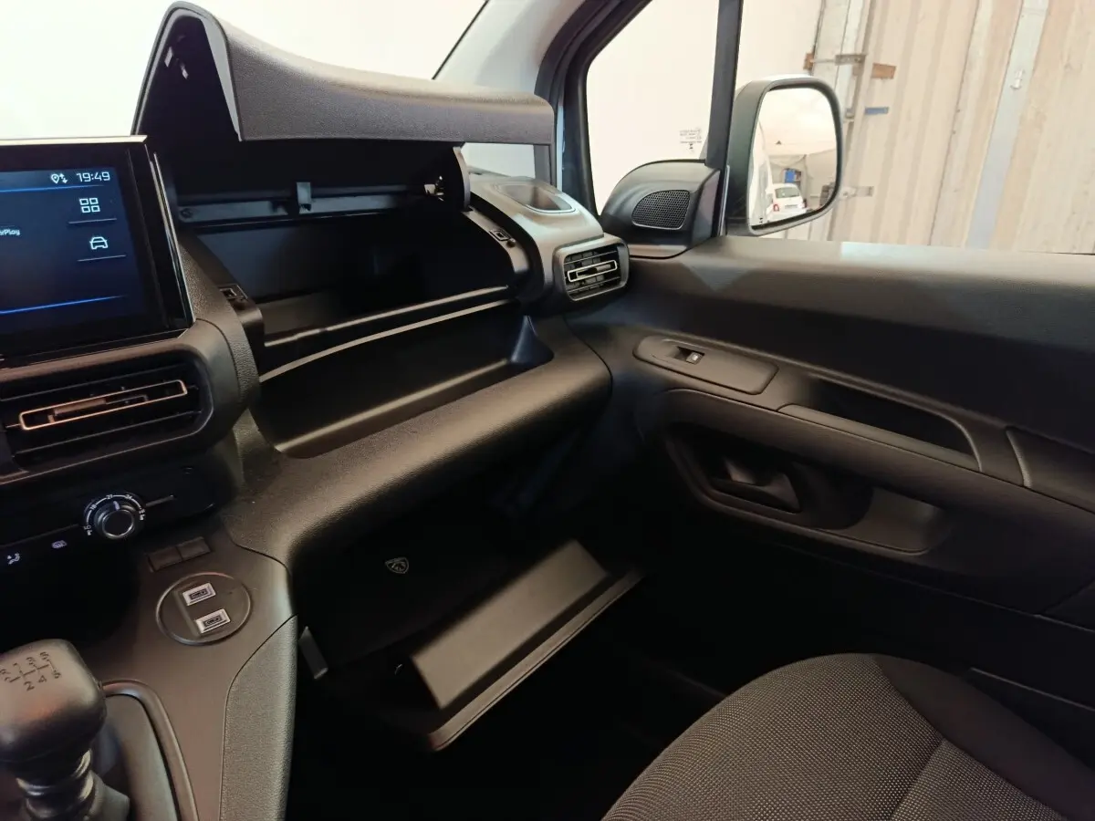 Intérieur avant droit du Peugeot Partner blanc 2026, montrant la boîte à gants ouverte et la console avec écran tactile.