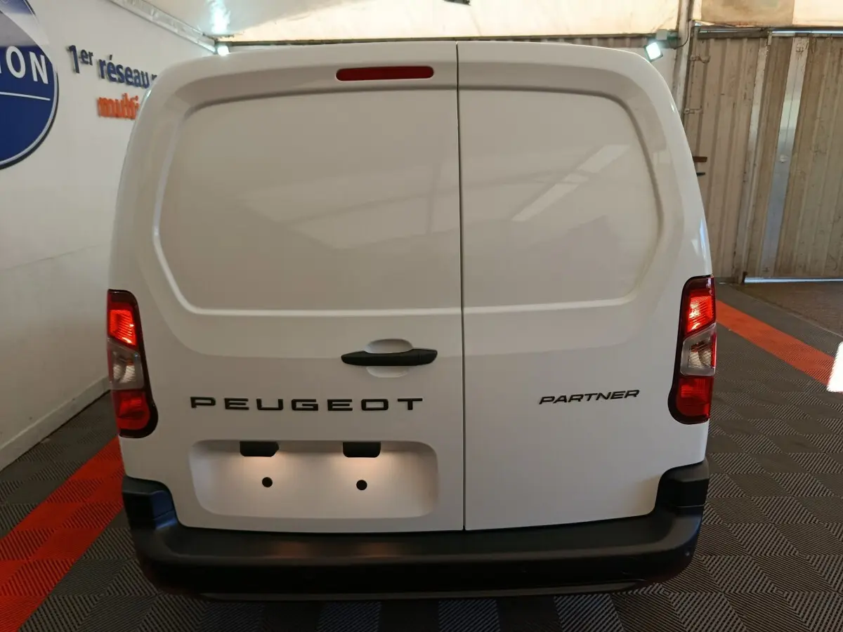 Vue arrière d’un utilitaire blanc Peugeot Partner Taille M avec portes battantes et feux rouges allumés.