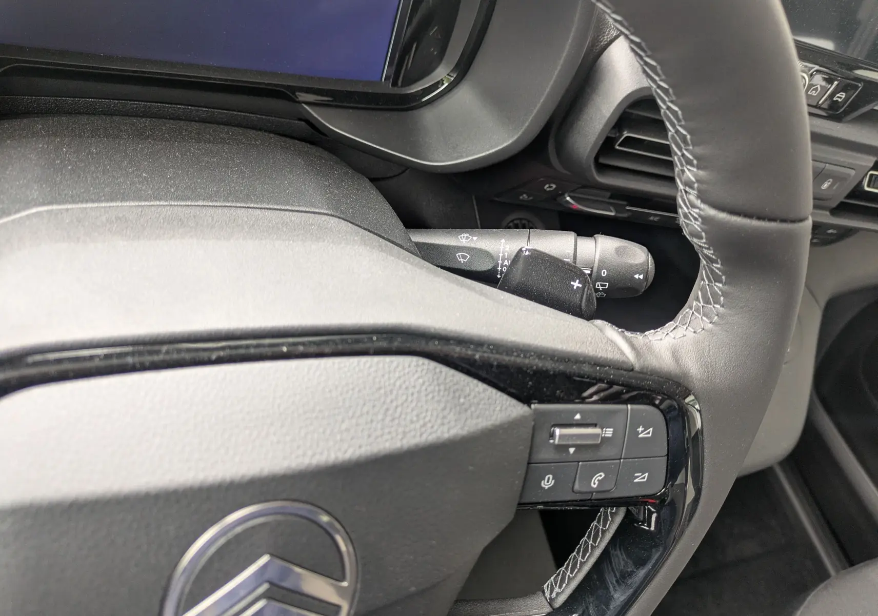 Gros plan sur le volant noir avec surpiqûres blanches du Citroën Berlingo 2025, montrant les commandes intégrées côté droit.