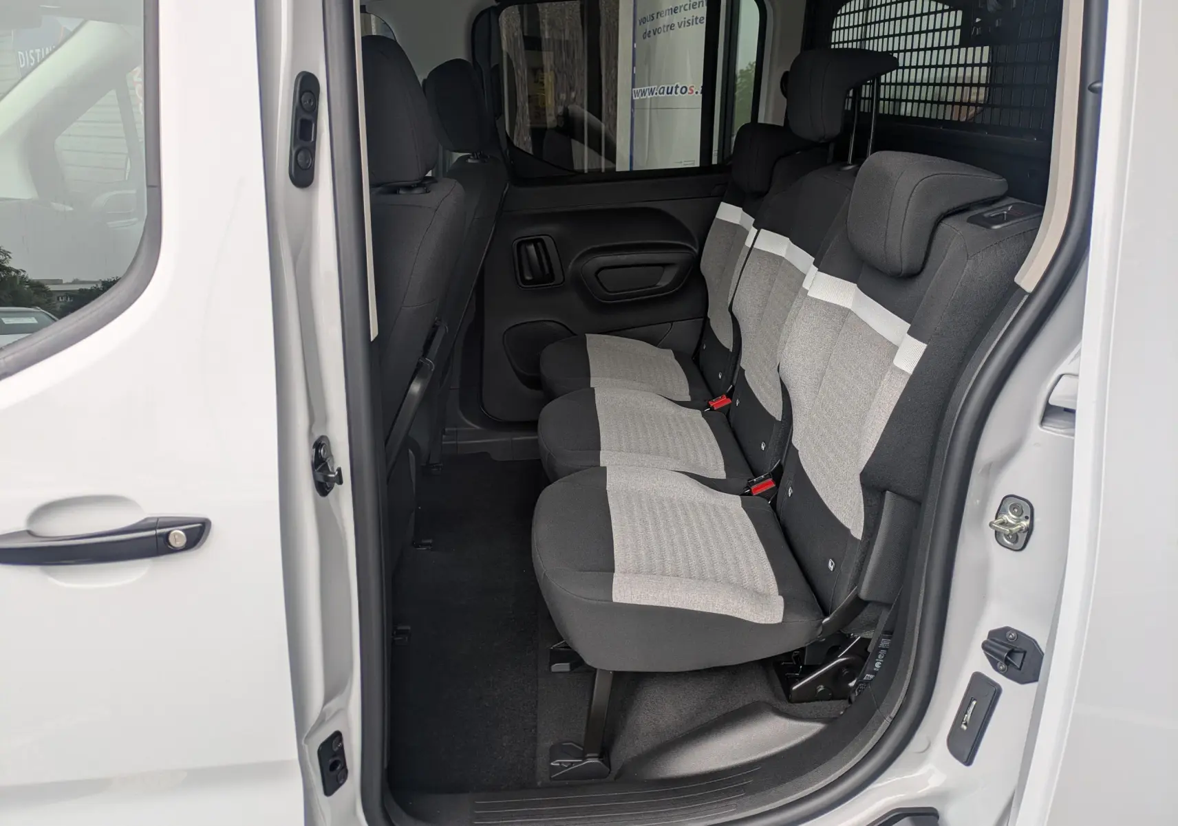Vue intérieure côté droit sur les sièges arrière gris et noir du Citroën Berlingo blanc 2025 avec porte coulissante ouverte.