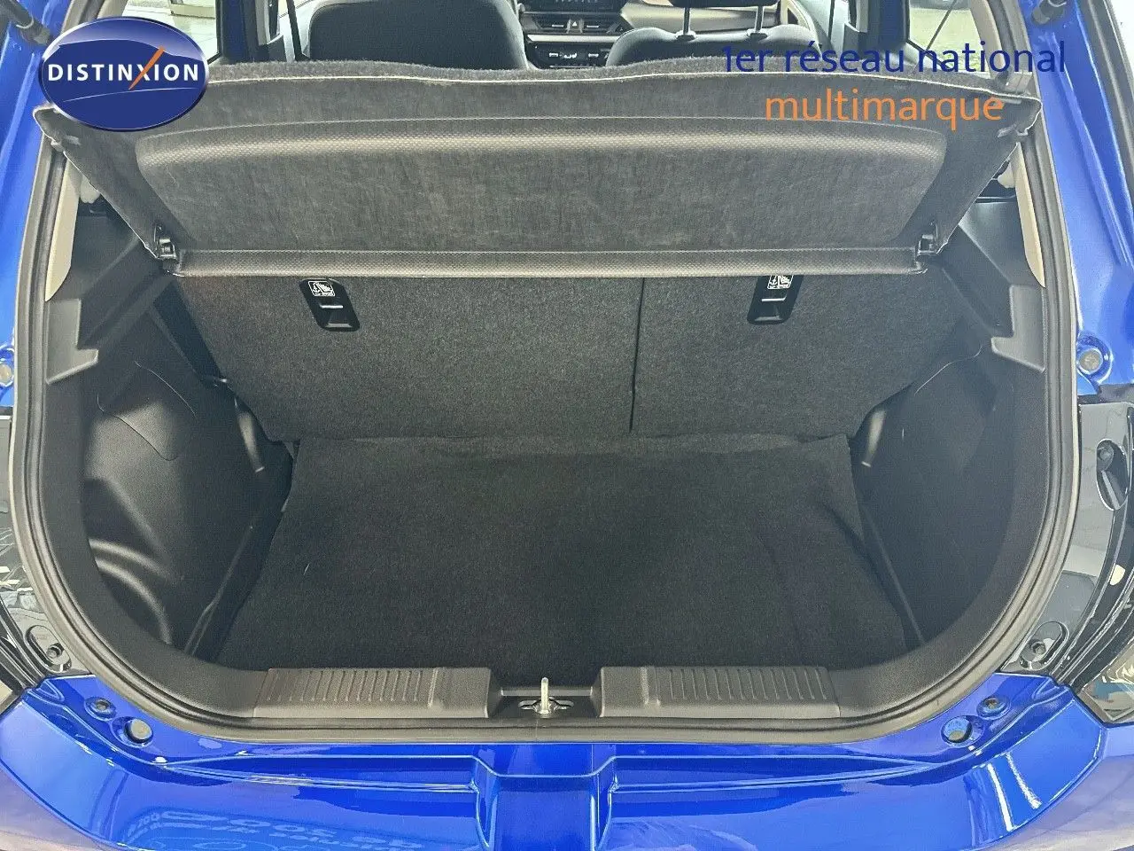 Coffre ouvert vu de l'arrière d'une Suzuki Swift 1.2 Pack Hybrid bleu 2024, montrant l'espace de chargement vide.