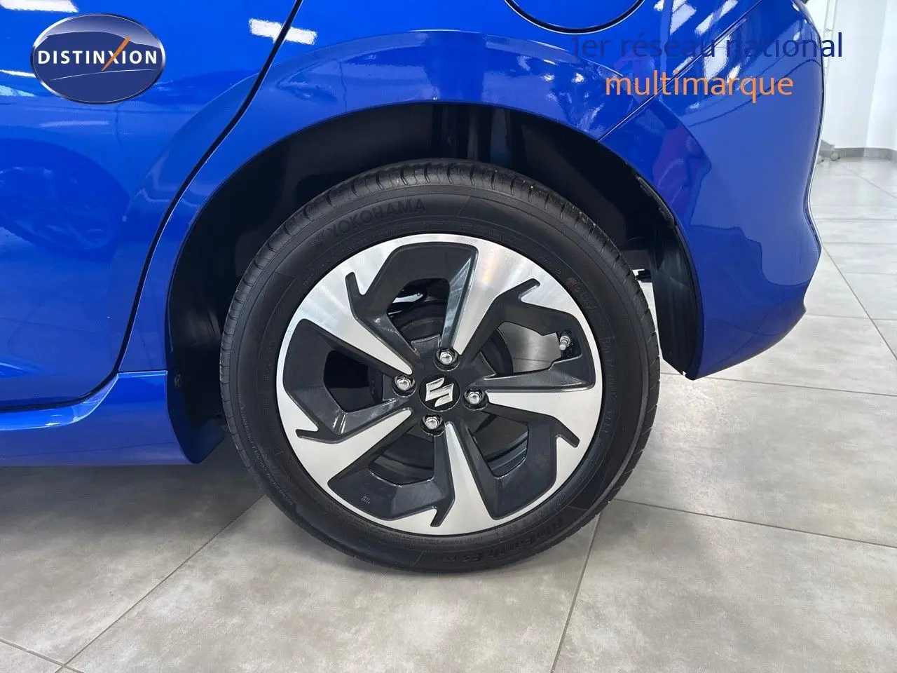 Gros plan sur la roue arrière droite d'une Suzuki Swift 1.2 Pack Hybrid 2024 bleu avec jante alliage au design moderne.