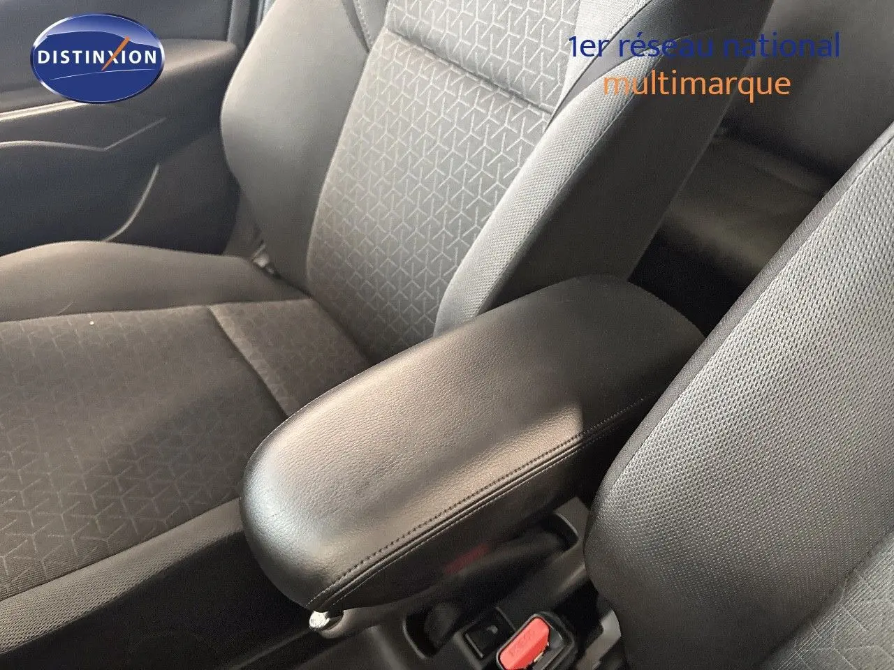 Gros plan sur l'accoudoir central noir et les sièges avant gris foncé à motifs dans l'habitacle d'une Suzuki Swift 2024.