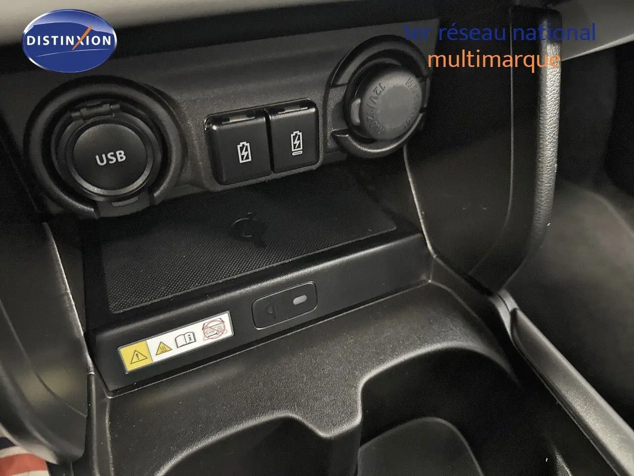 Gros plan sur la console centrale noire de la Suzuki Swift 1.2 Pack Hybrid 2024, montrant prises USB et ports de charge.