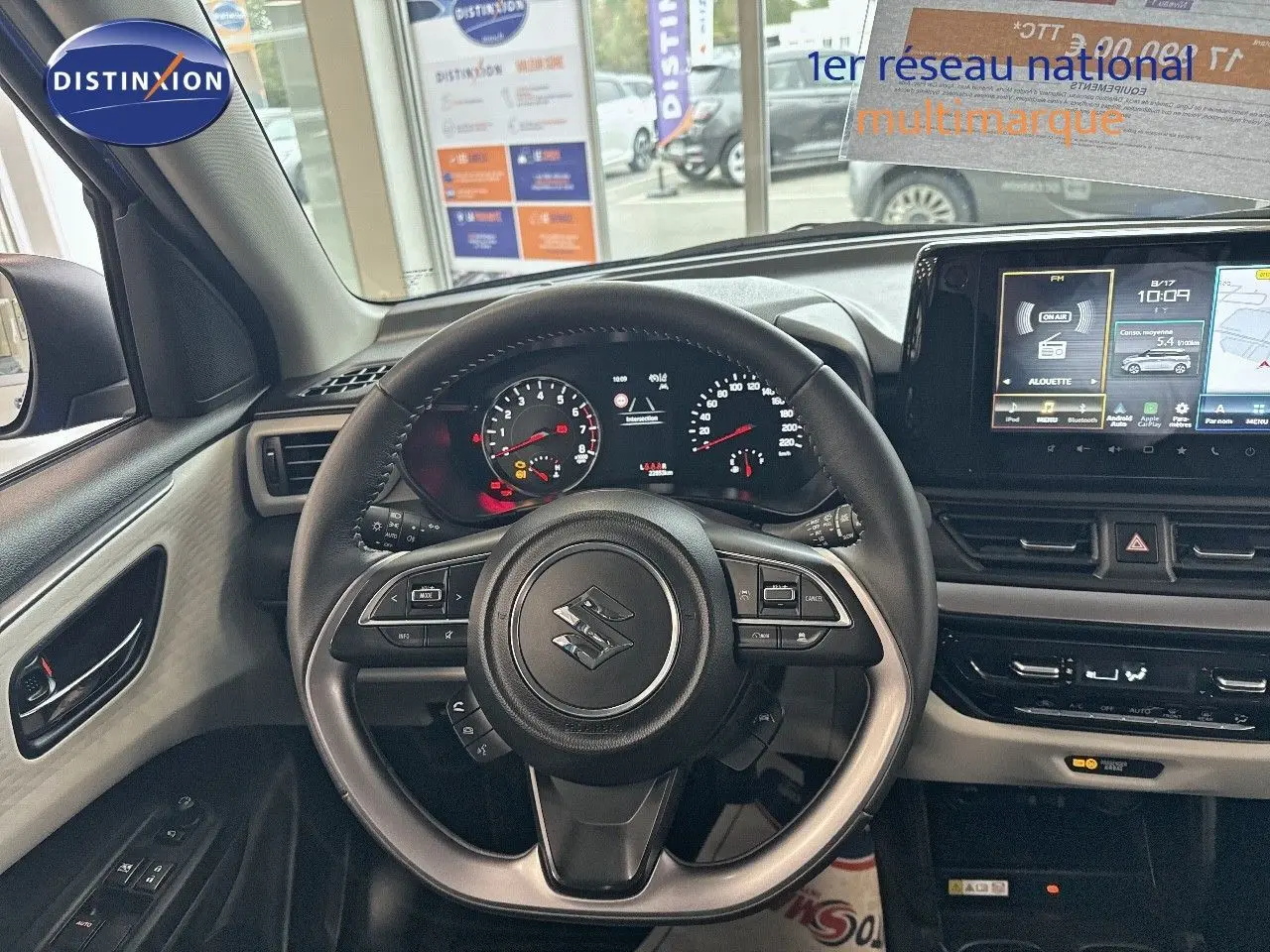 Vue intérieure centrée sur le volant et le tableau de bord de la Suzuki Swift 1.2 Pack Hybrid 2024, avec écran tactile et commandes au volant.